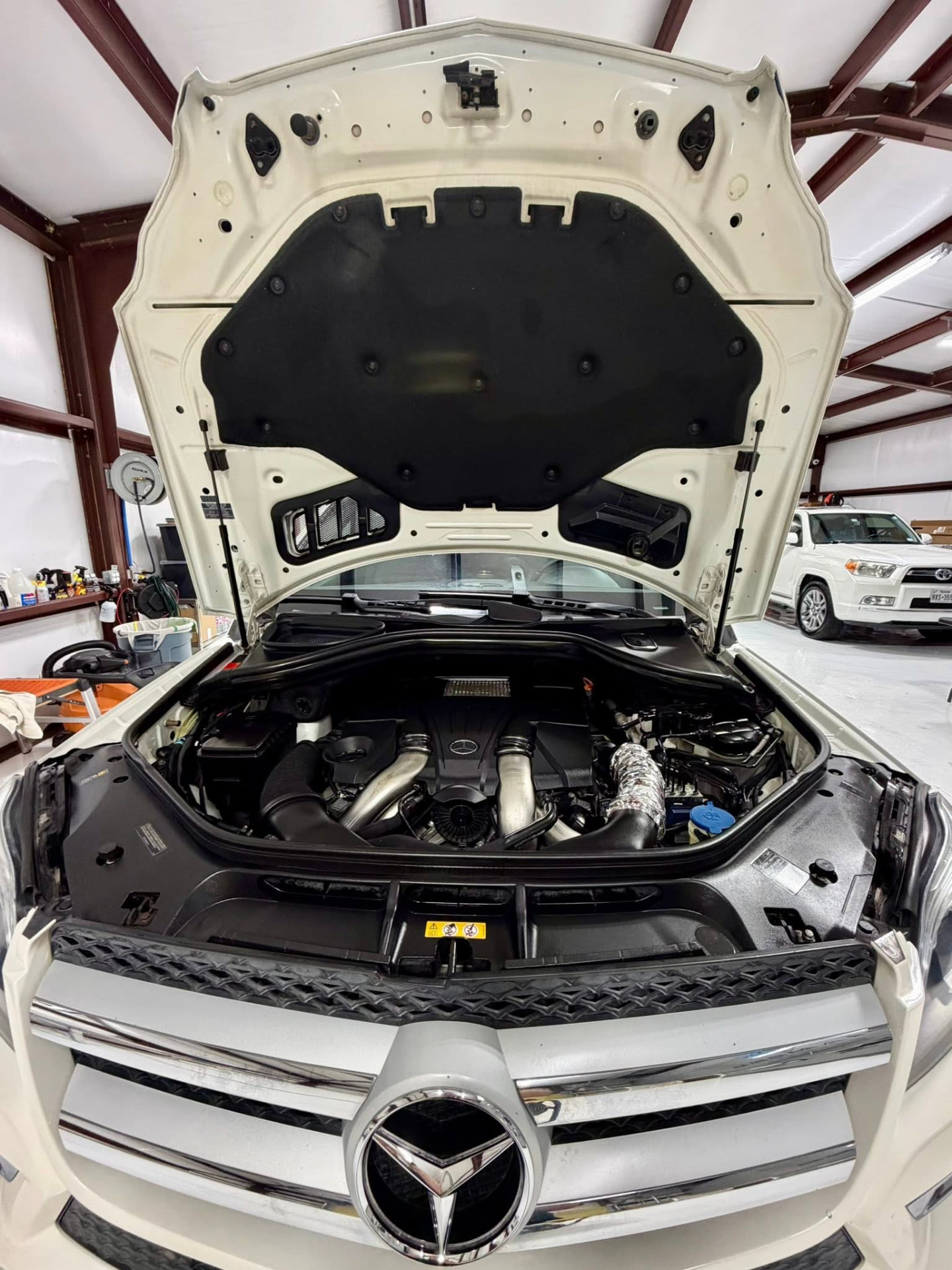 Clean engine bay of a white Mercedes-Benz V8 SUV after an engine bay detail
