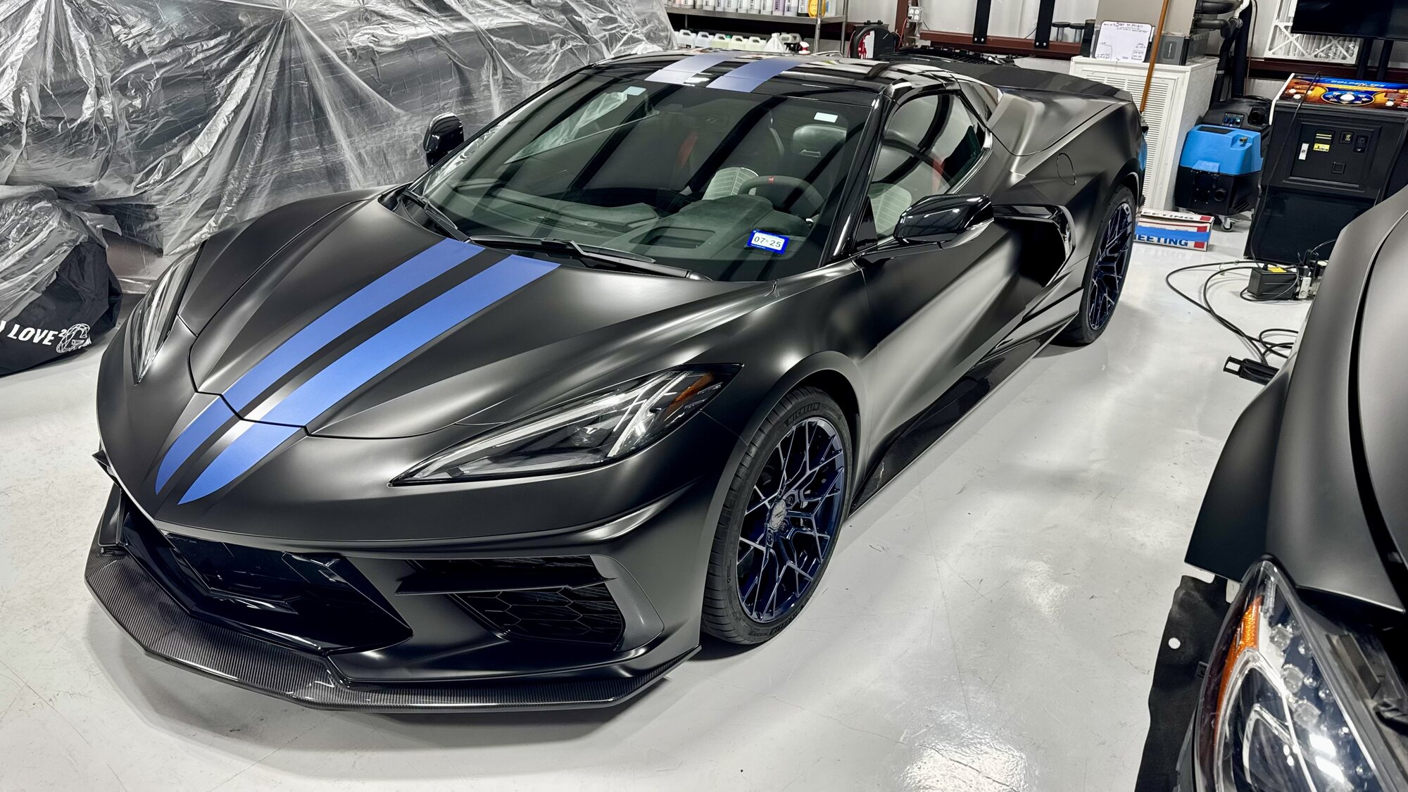 Corvette C8 convertible in satin black wrap with blue racing stripes