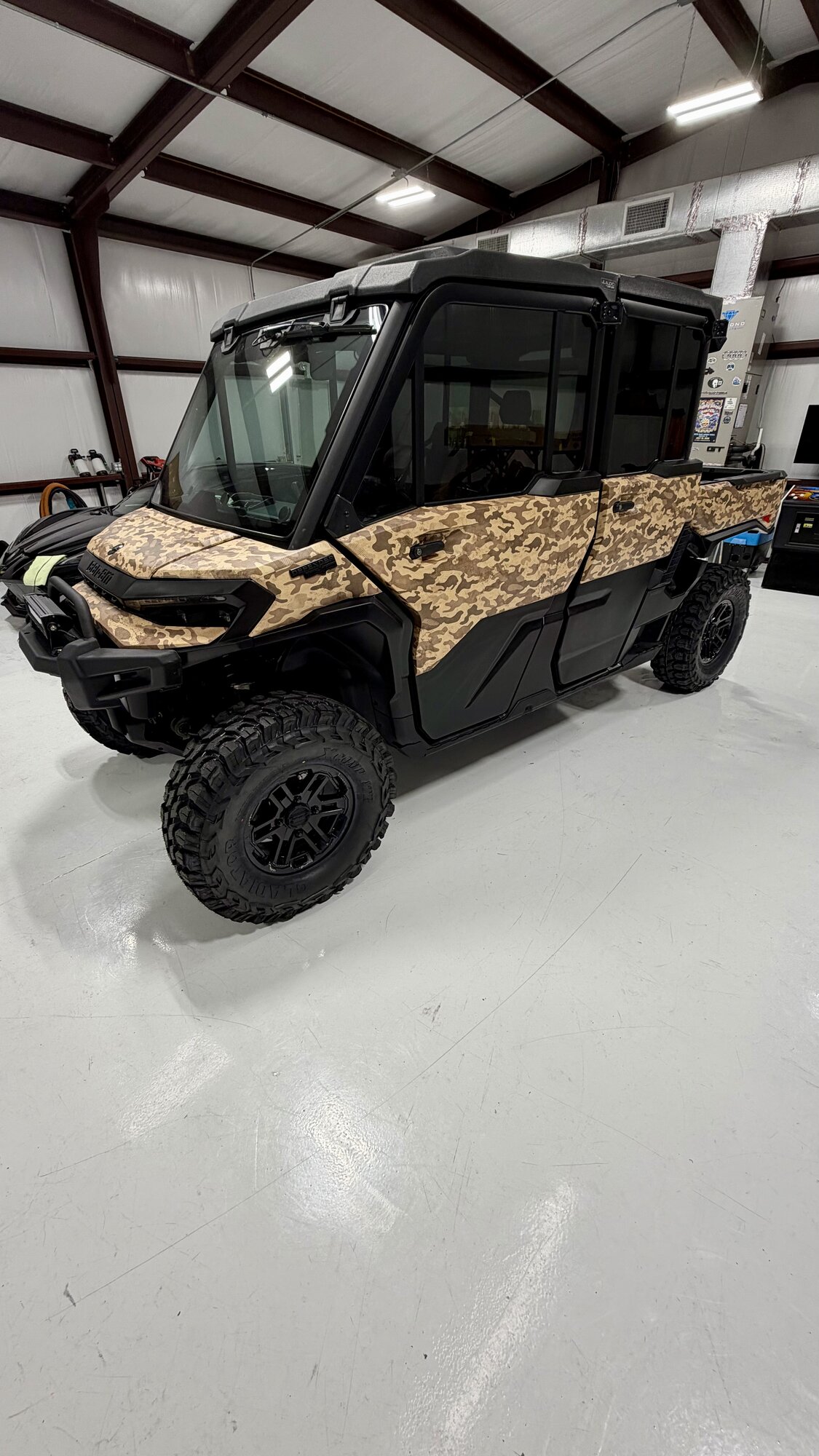 Black Can-Am Defender side-by-side with desert camo vinyl wrap